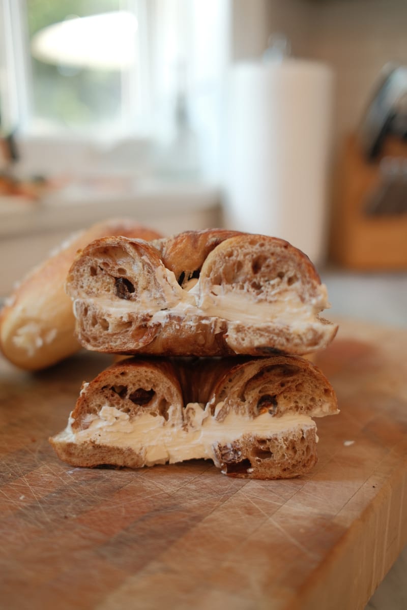 A cinnamon-raisin bagel sliced and spread with cream cheese